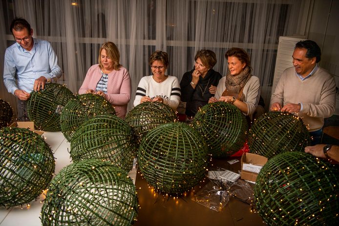 Vrijwilligers helpen mee om grote kerstbollen in elkaar te zetten en van verlichting te voorzien. De bollen komen in 15 straten in Zwammerdam te hangen als feestdagenverlichting.