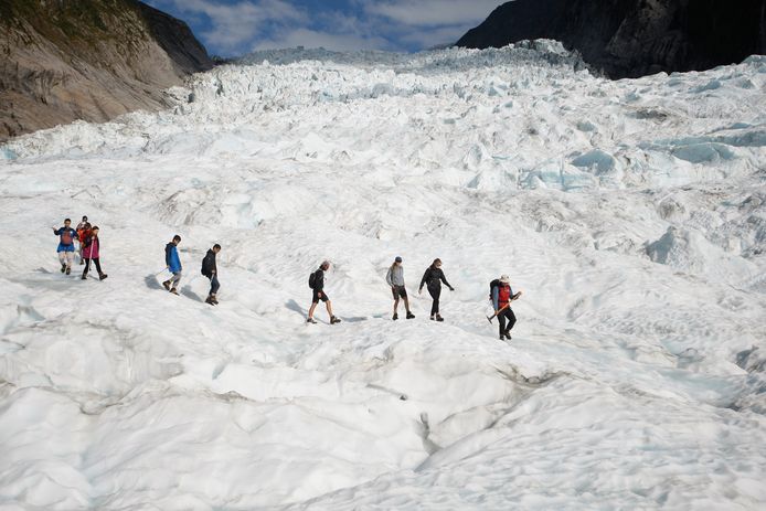 Toeristen die met een helikopter zijn afgezet, lopen op de Fox gletsjer in Nieuw-Zeeland. De gletsjers smelten erg snel door de opwarming van de aarde.