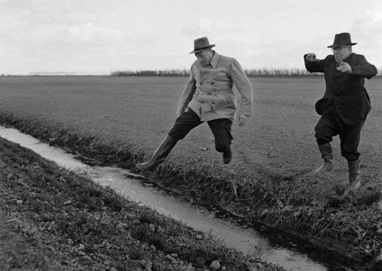 Sicco Mansholt (links) springt over een slootje bij zijn boerderij in de Wieringermeer in 1956. Beeld Nico Naeff / Nederlands Fotomuseum