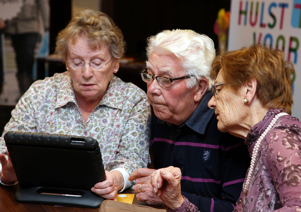 Hulst 201510190 Tabletcafe bij Curamus, Mariette van Eck, (links) maakt George de Loos en Mien Boddaert van Duysse wegwijs op de tablet