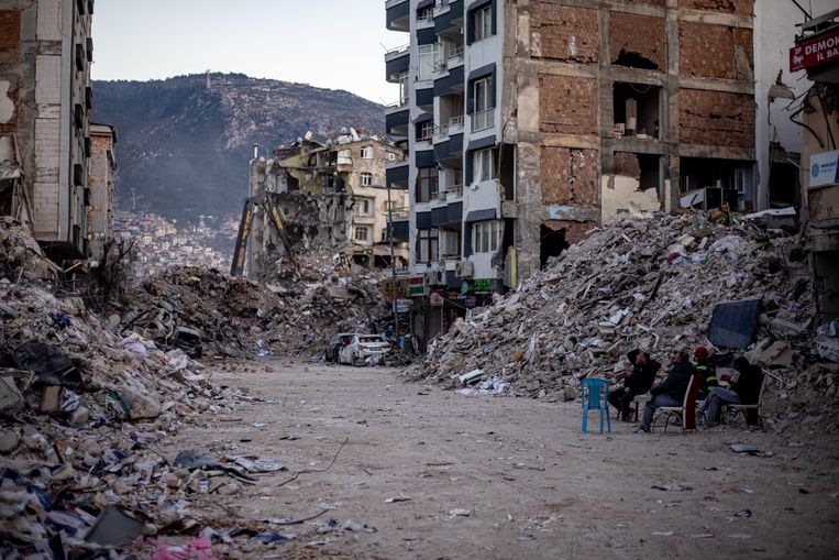 Mensen zitten op straat in het zwaar getroffen Hatay, Turkije. Het dodental is zondag opgelopen tot 46.000. Beeld ANP / EPA