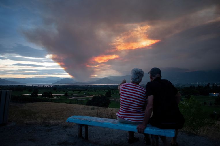 Een koppel kijkt toe naar de Mount Law natuurbrand, in de buurt van Okanagan Lake in Canada, eerder deze maand. Door het extreme weer vergroot de kans op natuurbranden. Beeld REUTERS