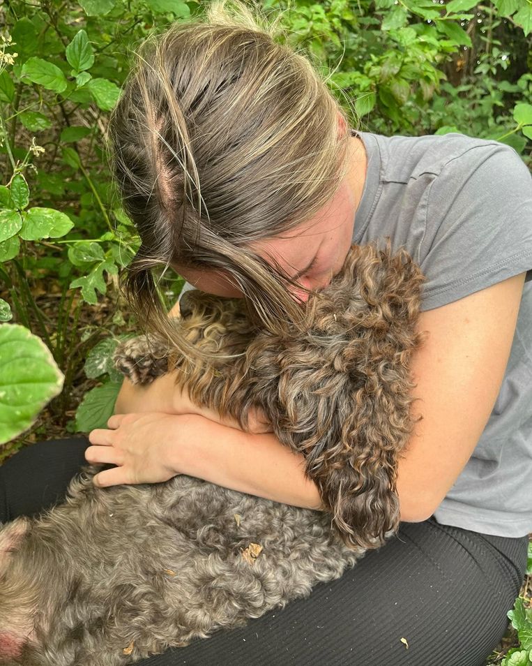 Amber Hollemans, nét herenigd met haar hondje, in de bosjes. Beeld Privé