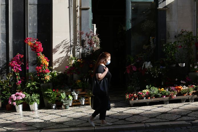Een vrouw wandelt voorbij een bloemenwinkel in Lissabon.