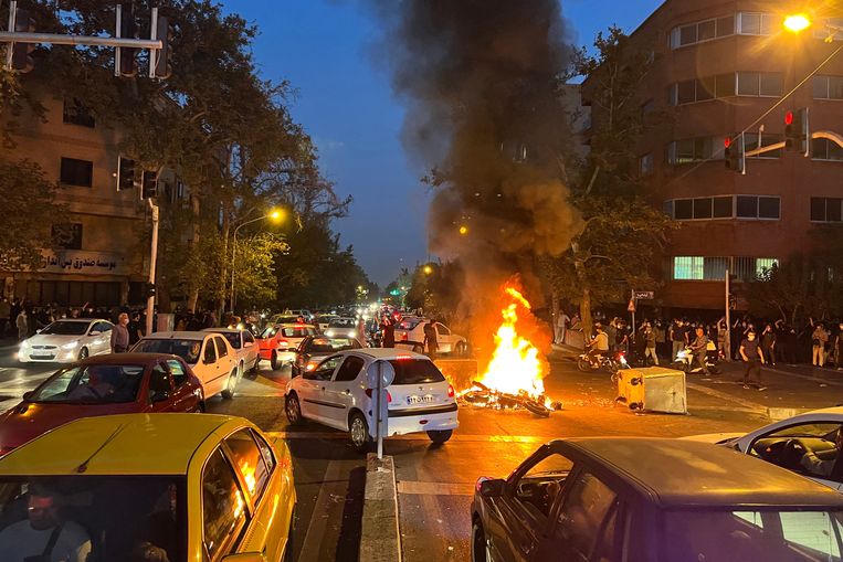 Een brandende politiemotor op een kruispunt in Teheran. De protesten liepen op meerdere plekken in Iran uit de hand op maandag. Naar verluidt zijn er meerdere demonstranten gedood door ordetroepen.  Beeld AFP
