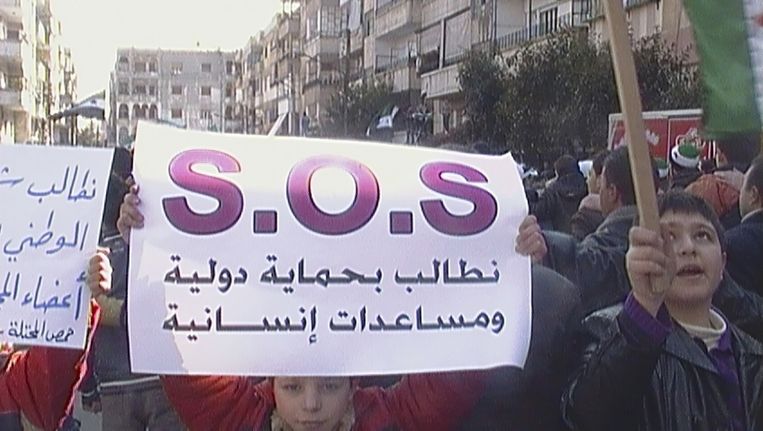 Demonstrant in Homs met een spandoek met de tekst: 'Eist internationale bescherming en humanitaire hulp'. Beeld reuters