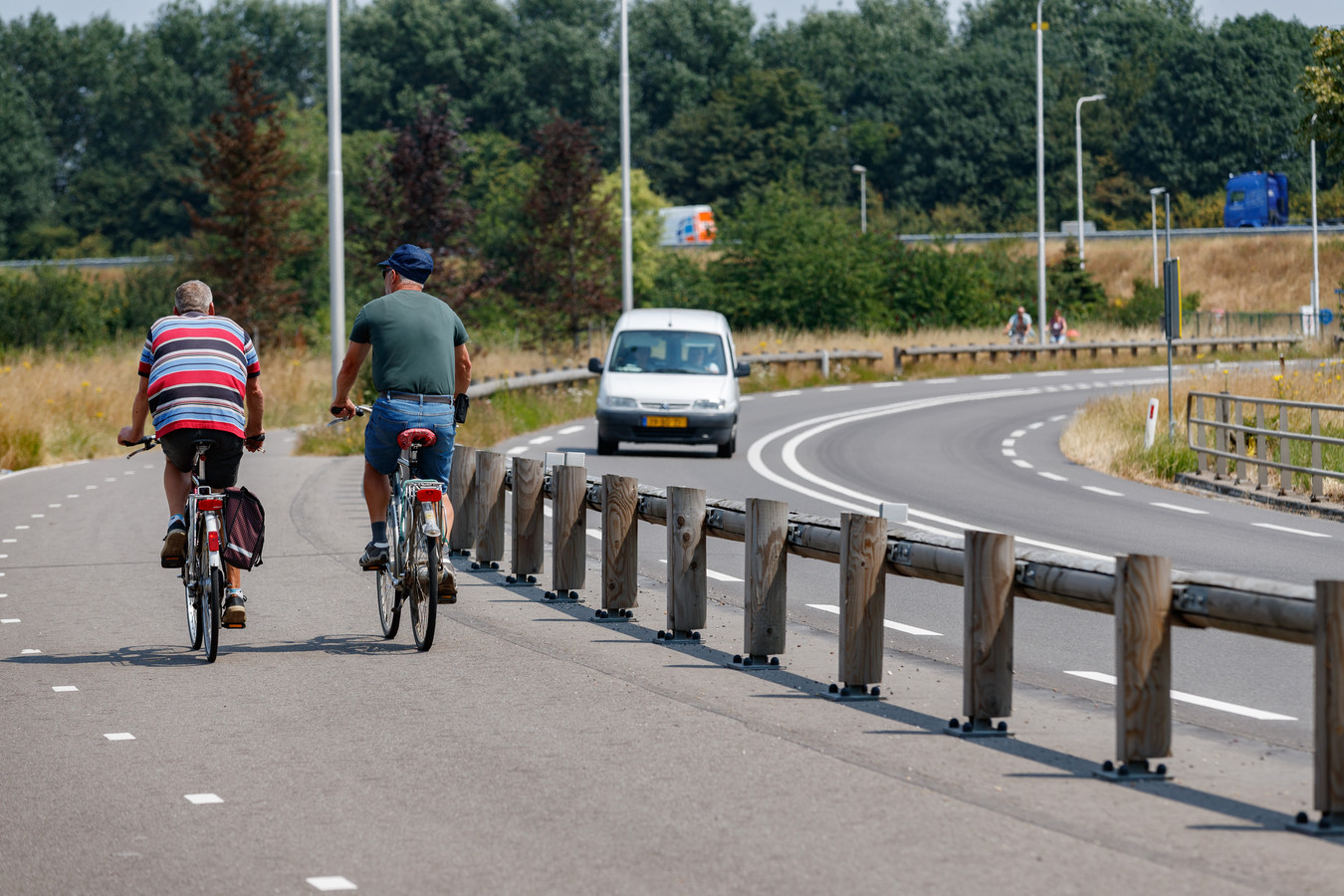 Een houten vangrail tussen Oud Gastel en de A17 scheidt het fietsverkeer van de autoweg N641.