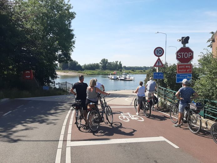 Fietsers wachten aan de Wageningse kant op de komst van het Lexkesveer.