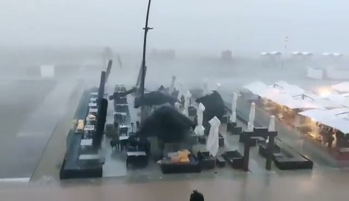 Screenshot uit de video. Op de beelden is te zien hoe parasols en tenten in het rond waaien door een kort maar hevig onweer in De Panne.