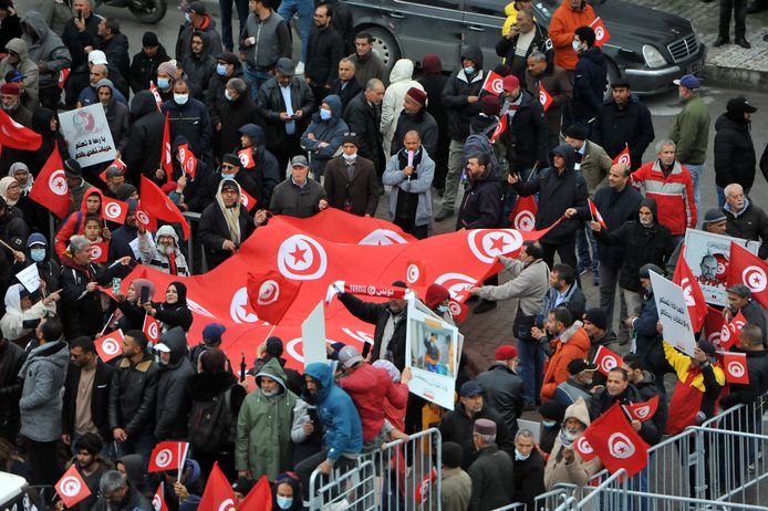 Tunesische betogers houden borden en nationale vlaggen omhoog tijdens een demonstratie tegen hun president, niet ver van het hoofdkwartier van de Tunesische Assemblee (parlement), in de hoofdstad Tunis.