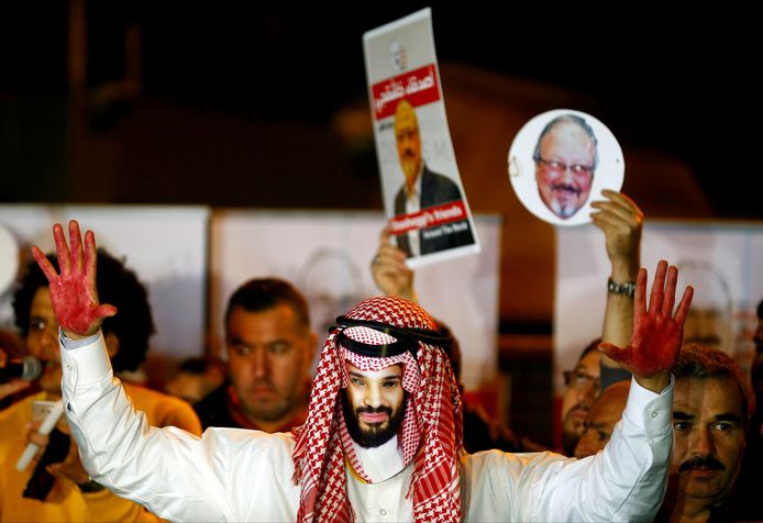 Betoger met een masker van de Saudische kroonprins, met op de achtergrond foto’s van Jamal Khashoggi.