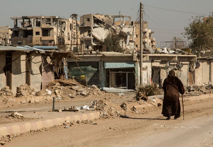 Een bewoonster loopt voorbij een verwoest gebouw in de verlaten stad Raqqa.