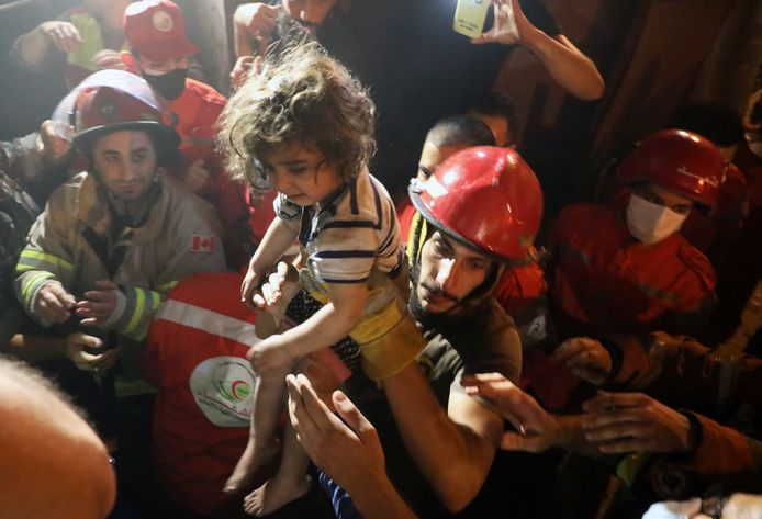 Reddingswerkers dragen een kind dat uit een gebouw werd gered nadat een brandstoftank ontplofte in Beiroet. (09/01/2020)