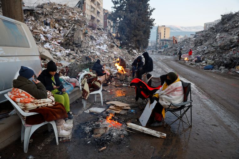 Overlevenden proberen zichzelf warm te houden bij een vuur in de stad Kahramanmaras. Beeld Reuters