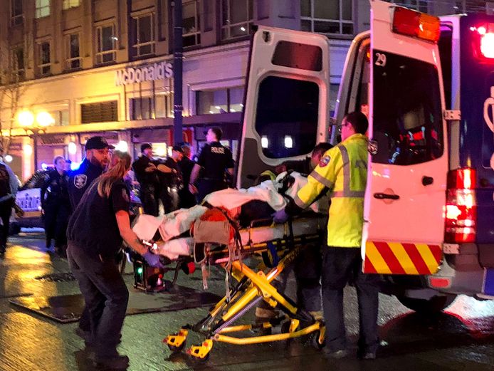 Een gewonde wordt met een brancard de ambulance ingedragen.