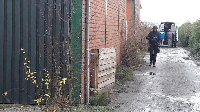 Zwaarbewapende agent achterop het perceel in Westdorpe waar eind vorig jaar een drugslab is gevonden.