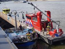Schip lekgeslagen in de Waal bij Nijmegen, brandweer pompt water uit schuit