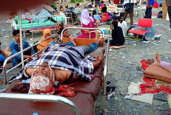 Mensen die de aardbeving overleefden, worden buiten aan het ziekenhuis opgevangen.