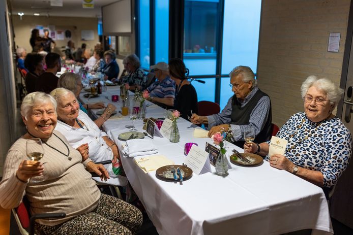Bewoners Door, Wil en Ank (vlnr) hebben zojuist hun voorgerecht op en genieten van een wijntje tijdens het diner in de gang van Nieuwehagen.