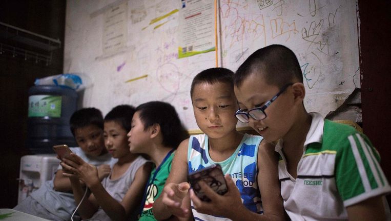 Kinderen spelen spelletjes op hun smartphone in een migrantengemeenschap in de buitenwijken van Peking, 17 augustus. Beeld afp