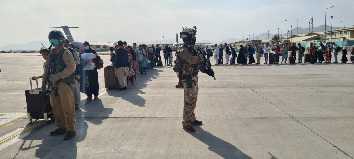 Vluchtende Afghanen die het platform van Kaboel-airport konden bereiken wachten in een lange rij op een Italiaans legervliegtuig. Beeld REUTERS