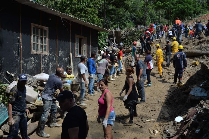 Lokale bewoners en reddingswerkers werken samen bij het zoeken naar slachtoffers van een aardverschuiving door zware stortregens in een favela in Guaruja, op 95 km van Sao Paulo.