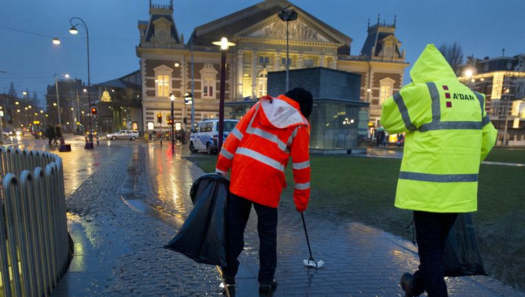 © ANP. Twee personen die zich hebben misdragen tijdens de jaarwisseling, zijn onder begeleiding van een ambtenaar van de reclassering begonnen met hun taakstraf op het Museumplein in Amsterdam. Beeld 