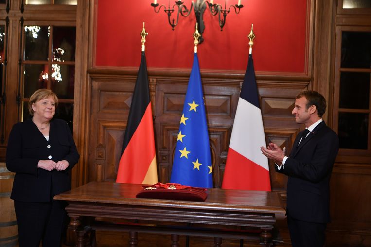 De Franse president Emmanuel Macron applaudisseert voor vertrekkend Duits bondskanselier Angela Merkel in Beaune, voor hij haar de de hoogste onderscheiding van het land, het Grootkruis van het Legioen van Eer, geeft. Beeld EPA