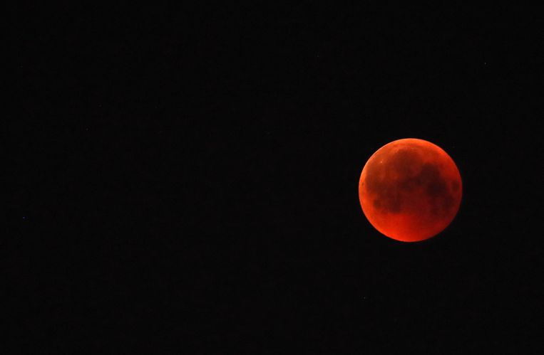 Bij een totale maaneclips heeft de verduisterde maan een oranjerode gloed. Beeld EPA