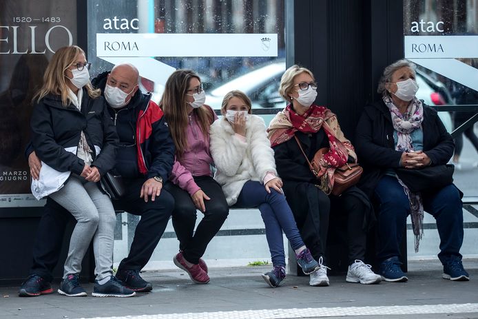 Mensen zitten met mondmasker op de bus te wachten in Rome.