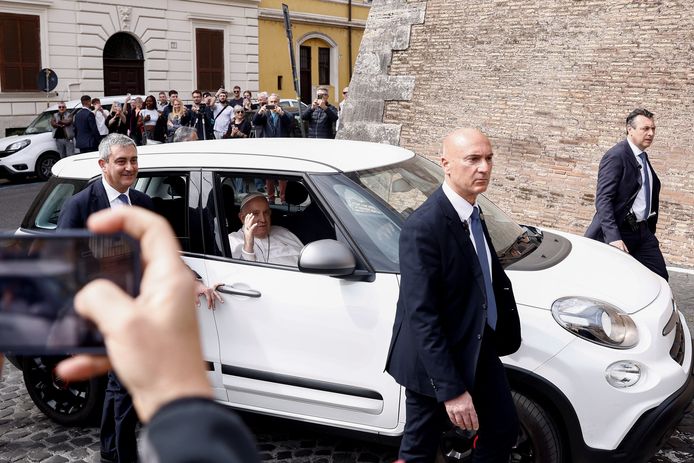 De paus wuift vanuit de auto nabij het Vaticaan.