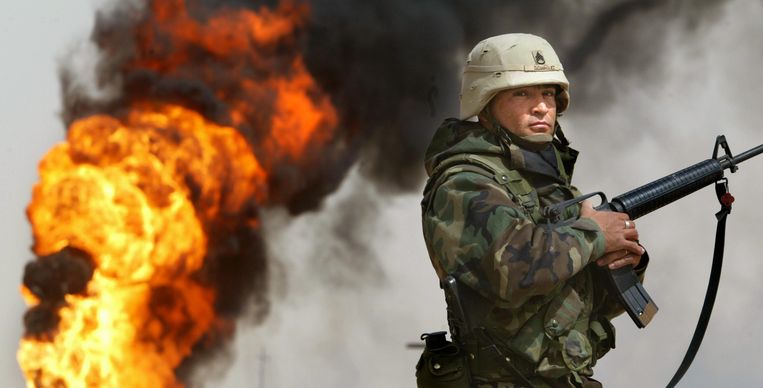 U.S. Army Staff Sergeant Robert Dominguez, of Mathis, Texas, stands guard next to a burning oil well at the Rumayla oil fields March 27, 2003 in Rumayla, Iraq. Several oil wells were set ablaze by retreating Iraqi troops in the Ramayla area, the second largest offshore oilfield in the country, near the Kuwaiti border. Beeld GETTY