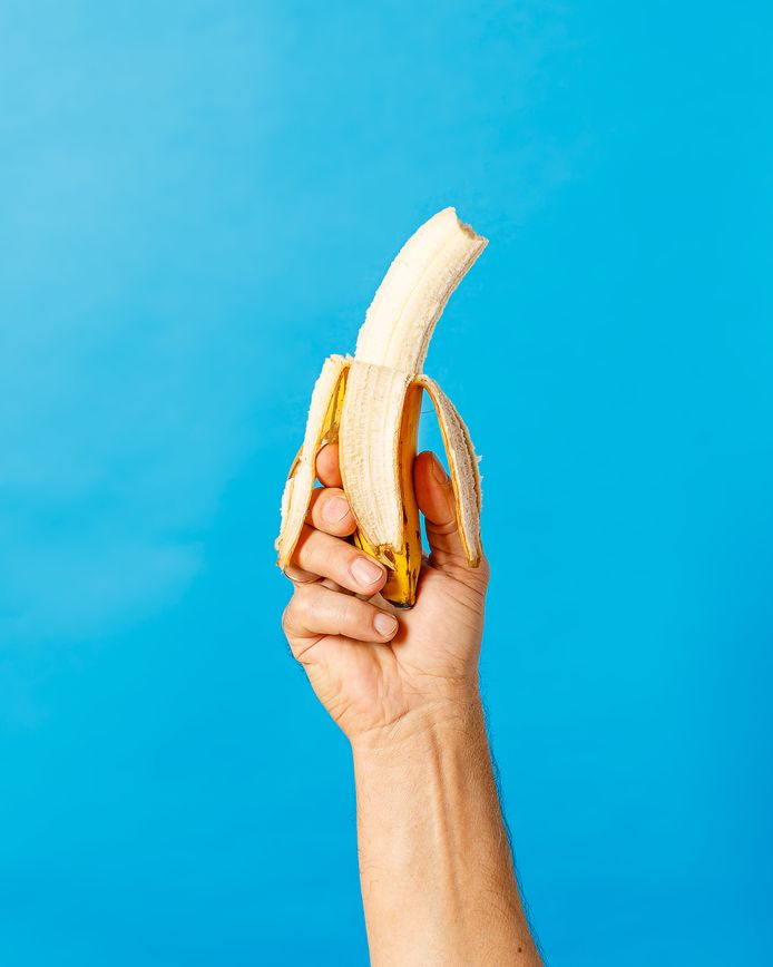 still life with hand holding banana on blue background