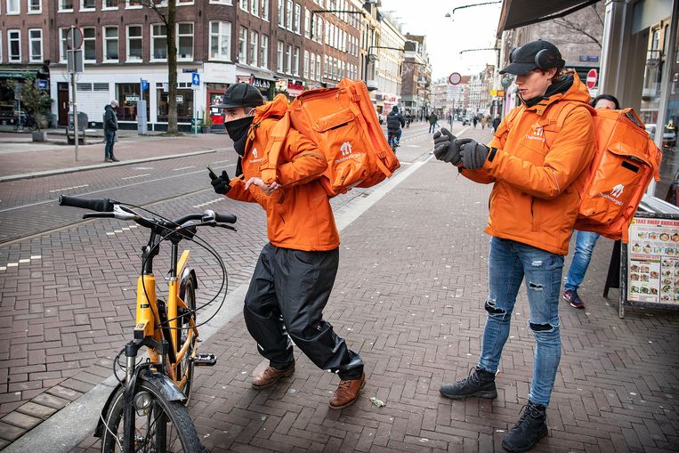 Twee bezorgers van Thuisbezorgd.nl in Amsterdam gaan met hun bestelling op pad. Beeld Guus Dubbelman / de Volkskrant