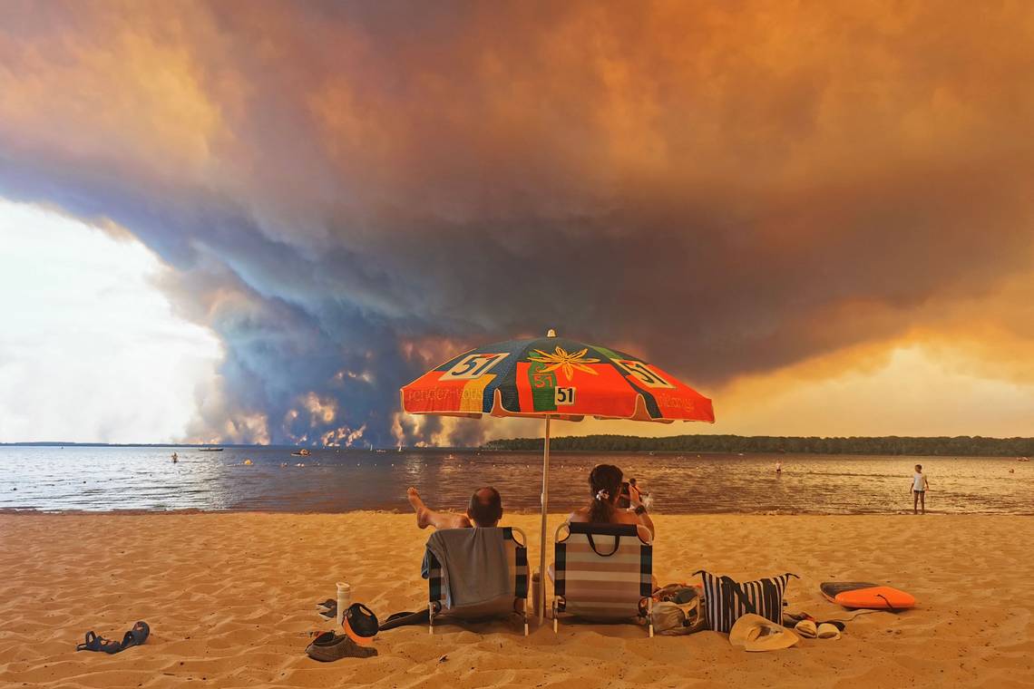 Twee strandstoelen, sandalen en een hemel vol rook: de foto die woede losmaakt over een brandende wereld