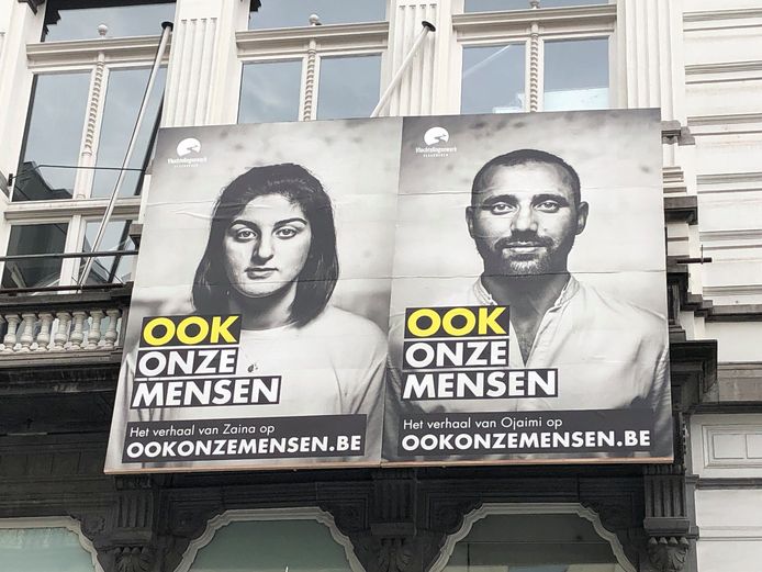 De grote affiches op de gevel van de Beursschouwburg tonen portretten van vier vluchtelingen die in België neerstreken en hulp kregen van Vluchtelingenwerk Vlaanderen.