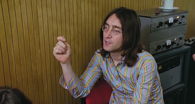 John Lennon in babyblauw overhemd met regenboogstreepjes en halve knoopjessluiting.  Beeld 