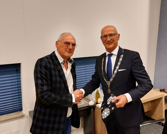 Raadslid Peter Meijs (l) wenst scheidend burgemeester Rob van der Zwaag veel succes en geeft hem enkele cadeaubonnen.