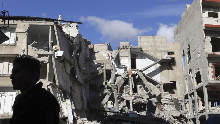 Een man staat voor een gebouw in Damascus dat is vernietigd na een luchtaanval van het Syrische leger. Beeld reuters