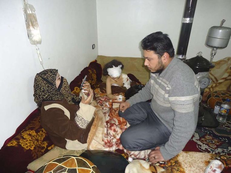 Een meisje (midden) raakte gewond tijdens gevechten op 5 februari. Ze zit naast haar familieleden in Babo Amro, een woonwijk in Homs. Datum van publicatie onbekend.  <br /> Beeld reuters