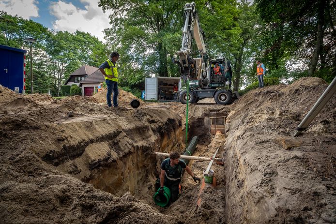 Gecoacht door een kraanmachinist laat de Woensdrechtse wethouder Jeffrey van Agtmaal een infiltratiebuis voor regenwater in de bodem zakken aan de Sparrenlaan in Putte. Dat moet helpen in de strijd tegen overlast bij hoosbuien.