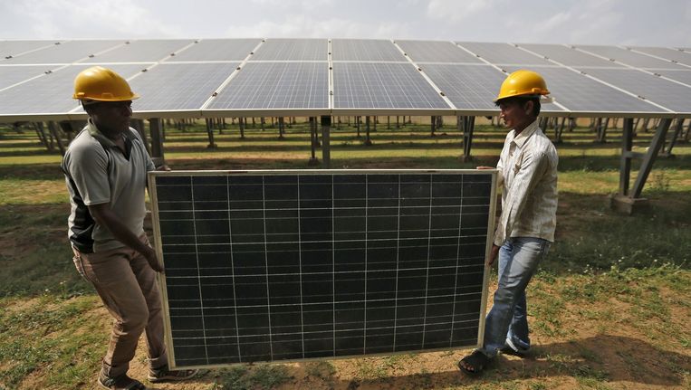 Arbeiders plaatsen een zonnepaneel in India. Beeld reuters