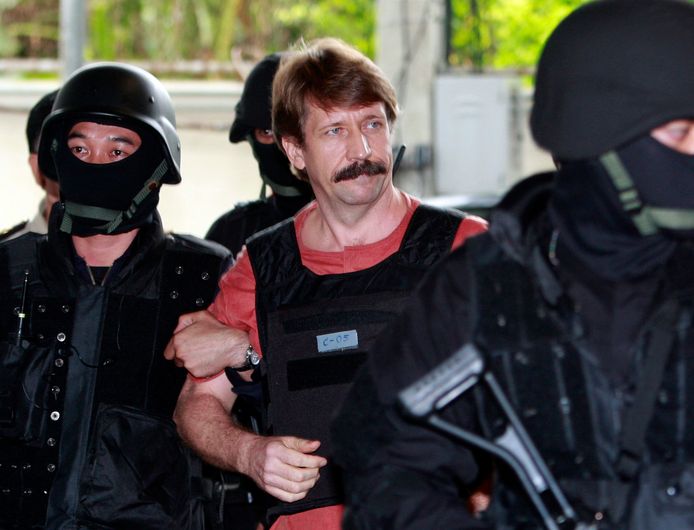De Russische wapenhandelaar Viktor Bout (m) begeleid door gewapende Thaise politiecommando’s, eind 2010 in Bangkok.