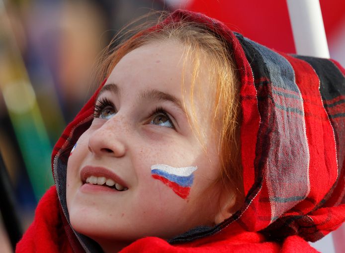 Een meisje kijkt omhoog naar een podium waar Poetin een toespraak zal geven.