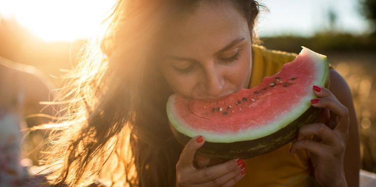 Young woman eating watermelon outdoors Beeld Getty Images