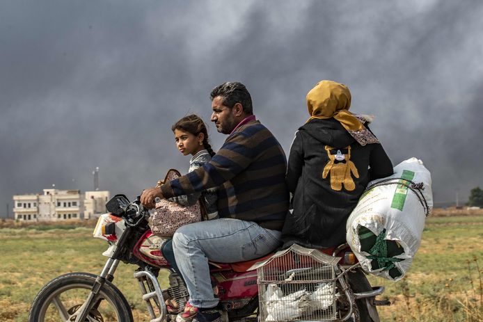 Een Syrische familie ontvlucht de gevechtszone. De rook op de achtergrond is van brandende autobanden die de Koerdische milities gebruiken om het zicht van piloten te bemoeilijken.