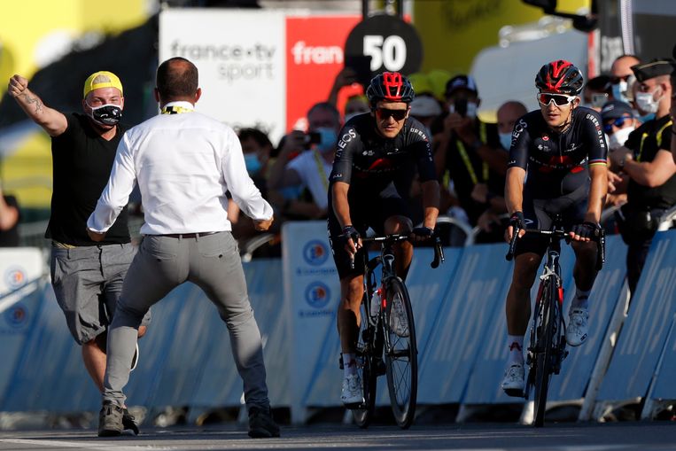 Een medewerker van de Tour haalt een fan van het parcours als de Poolse wielrenner Michal Kwiatkowski (rechts) richting de finish fietst om de etappe te winnen.  Beeld AP