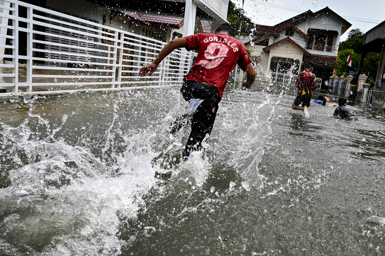 Kinderen in het water nadat hevige regenval overstromingen veroorzaakte in Banda Aceh, Indonesië.

 Beeld AFP
