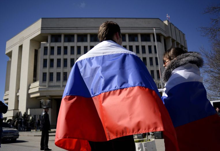 Een stel met Russische vlaggen omgeslagen voor het parlement op de Krim, op 17 maart 2014.  Beeld EPA