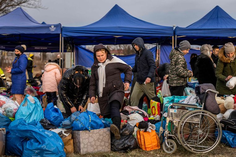 Oekraïense vluchtelingen zoeken naar spullen van hun gading aan de Poolse zijde van de grensovergang bij Medyka in Zuidoost-Polen. Beeld WOJTEK RADWANSKI/AFP